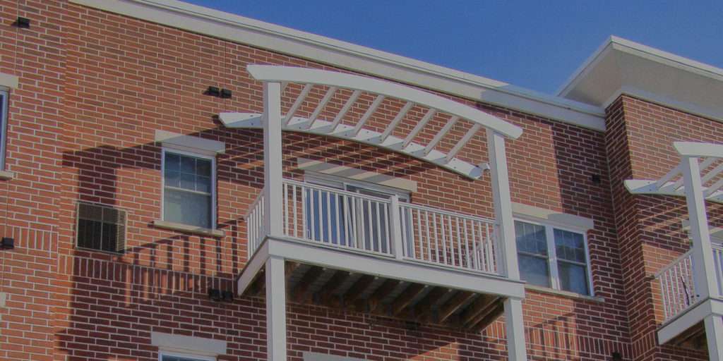 Close up of white balconies added to the side of a brick building as part of a commercial remodeling project